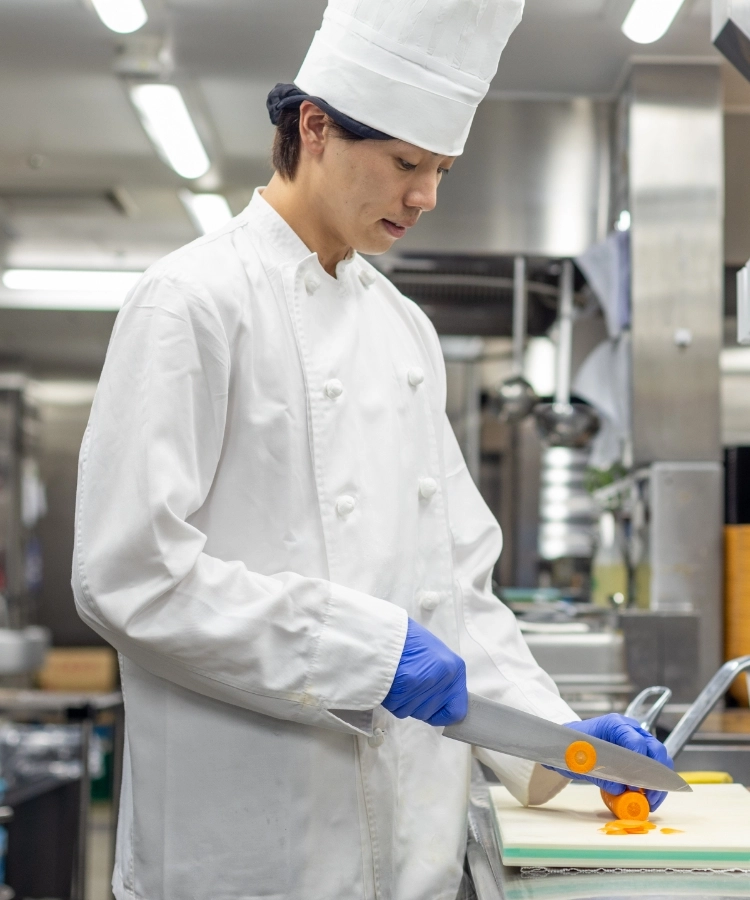 H.M.さんインタビューキービジュアル　厨房で包丁を使っている写真