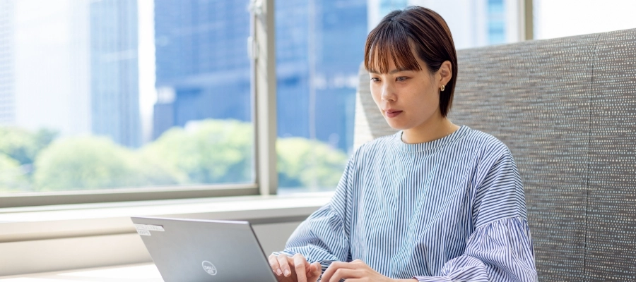 R.S.さん仕事風景　窓側のソファ席に座ってパソコン作業をしている写真