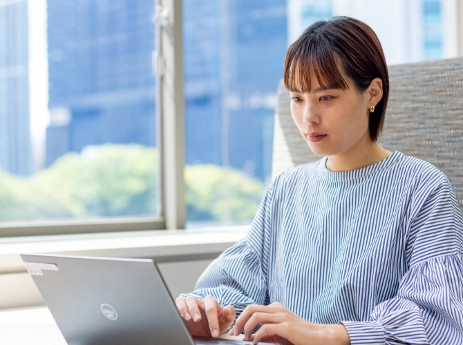 R.S.さん仕事風景　窓側のソファ席に座ってパソコン作業をしている写真