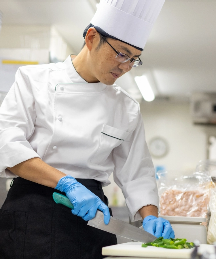 T.Y.さんインタビューキービジュアル　厨房で野菜を切っている写真