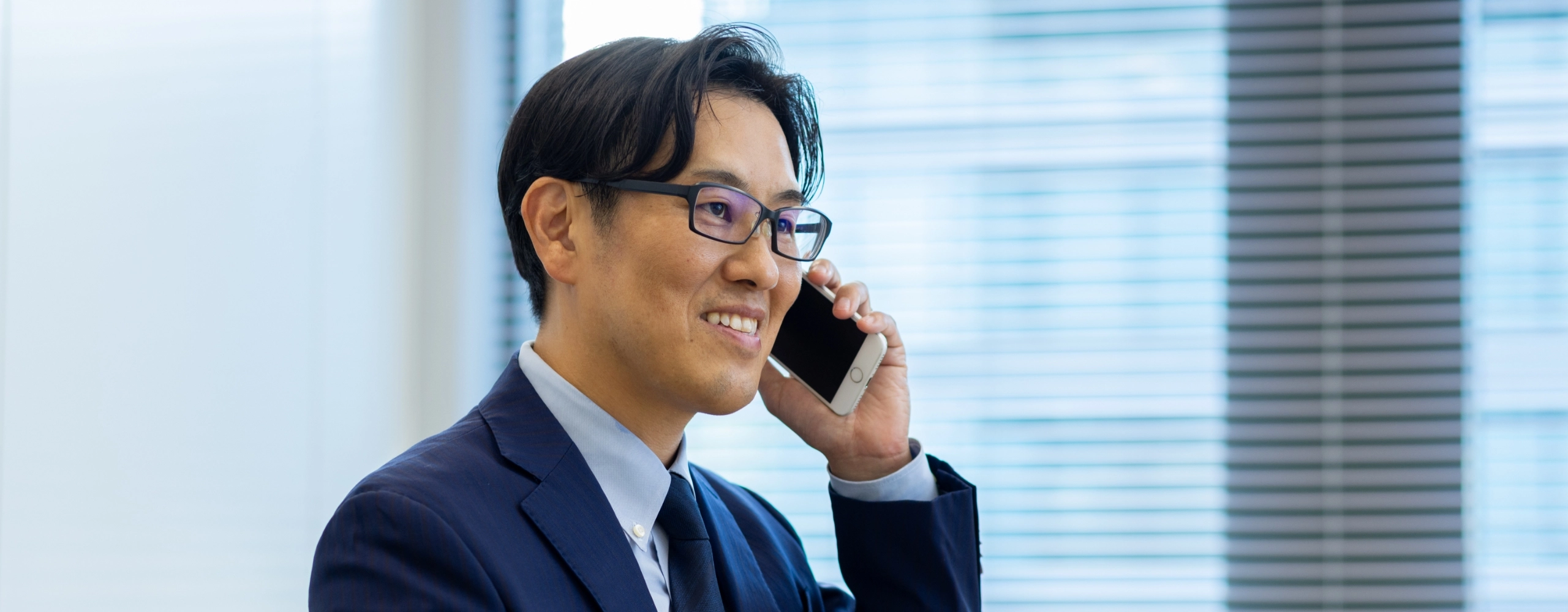 S.K.さんインタビューキービジュアル　大きな窓をバックに電話で会話している写真